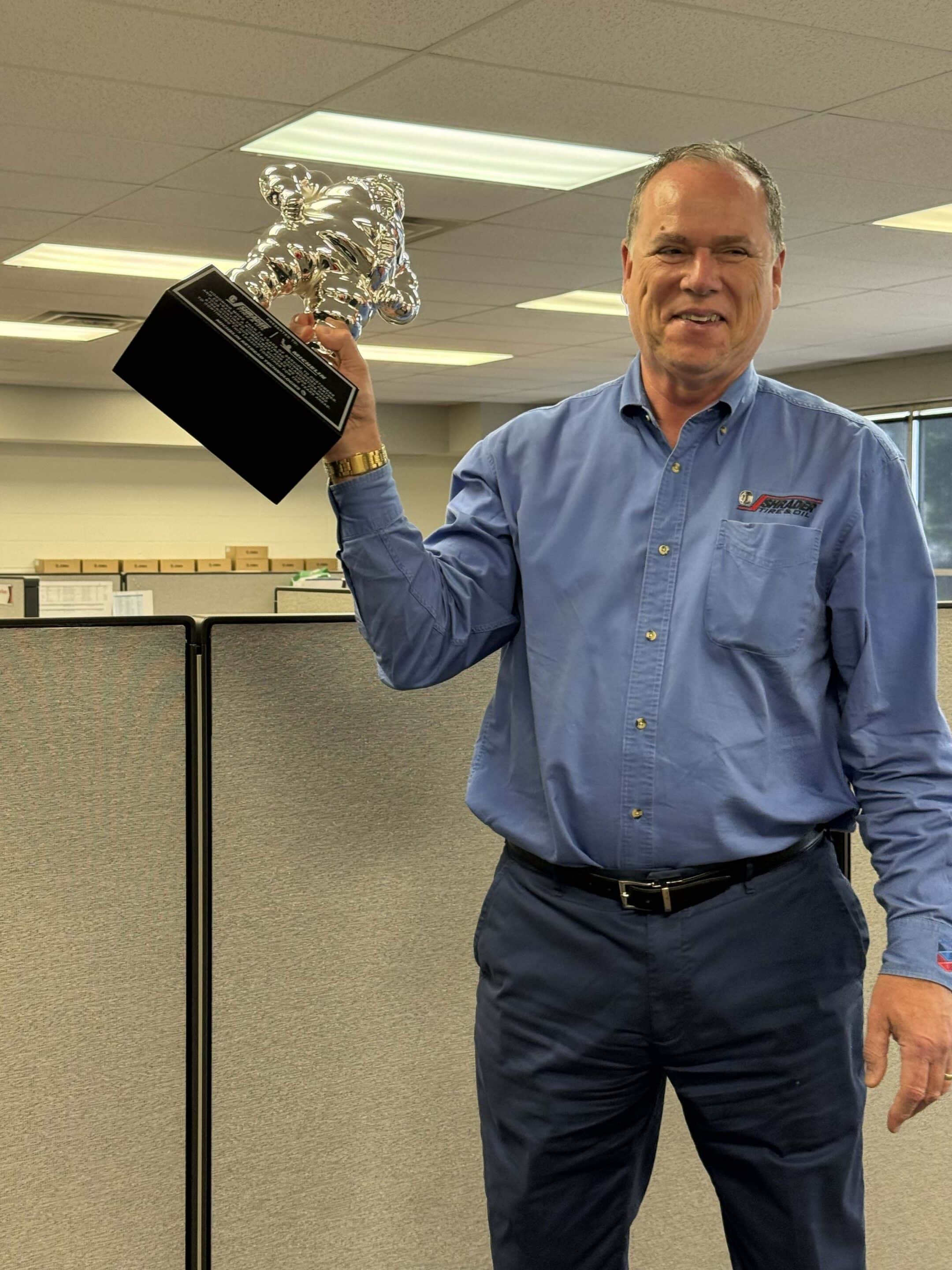 John Shrader of Shrader Tire & Oil holding the Michelin Retread Technologies Bibendum trophy at Toledo headquarters