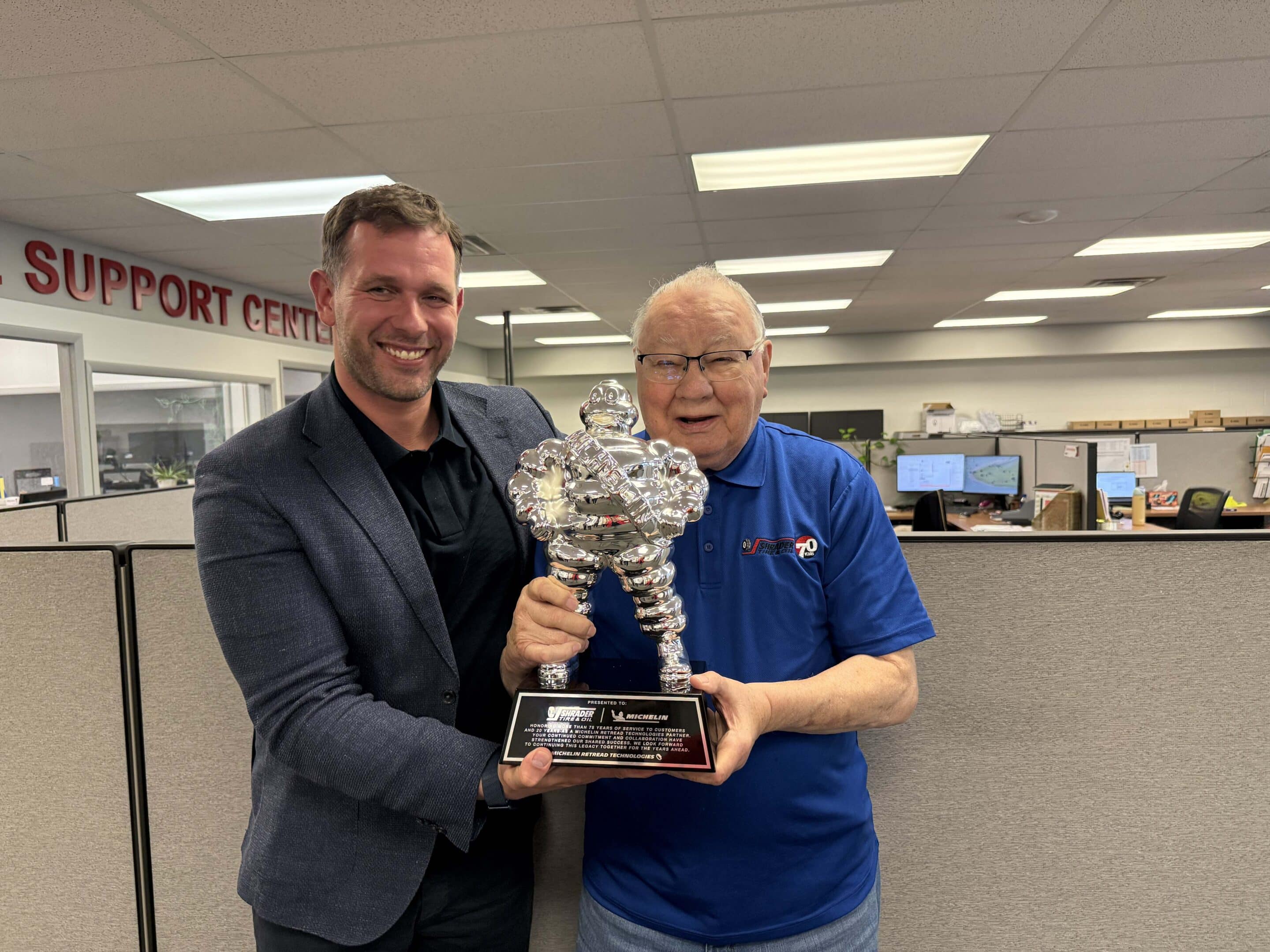 Jim Shrader Jr. of Shrader Tire & Oil and Mindaugas Kelpša of Michelin holding the Michelin Retread Technologies 20-year partnership award at STO Toledo headquarters